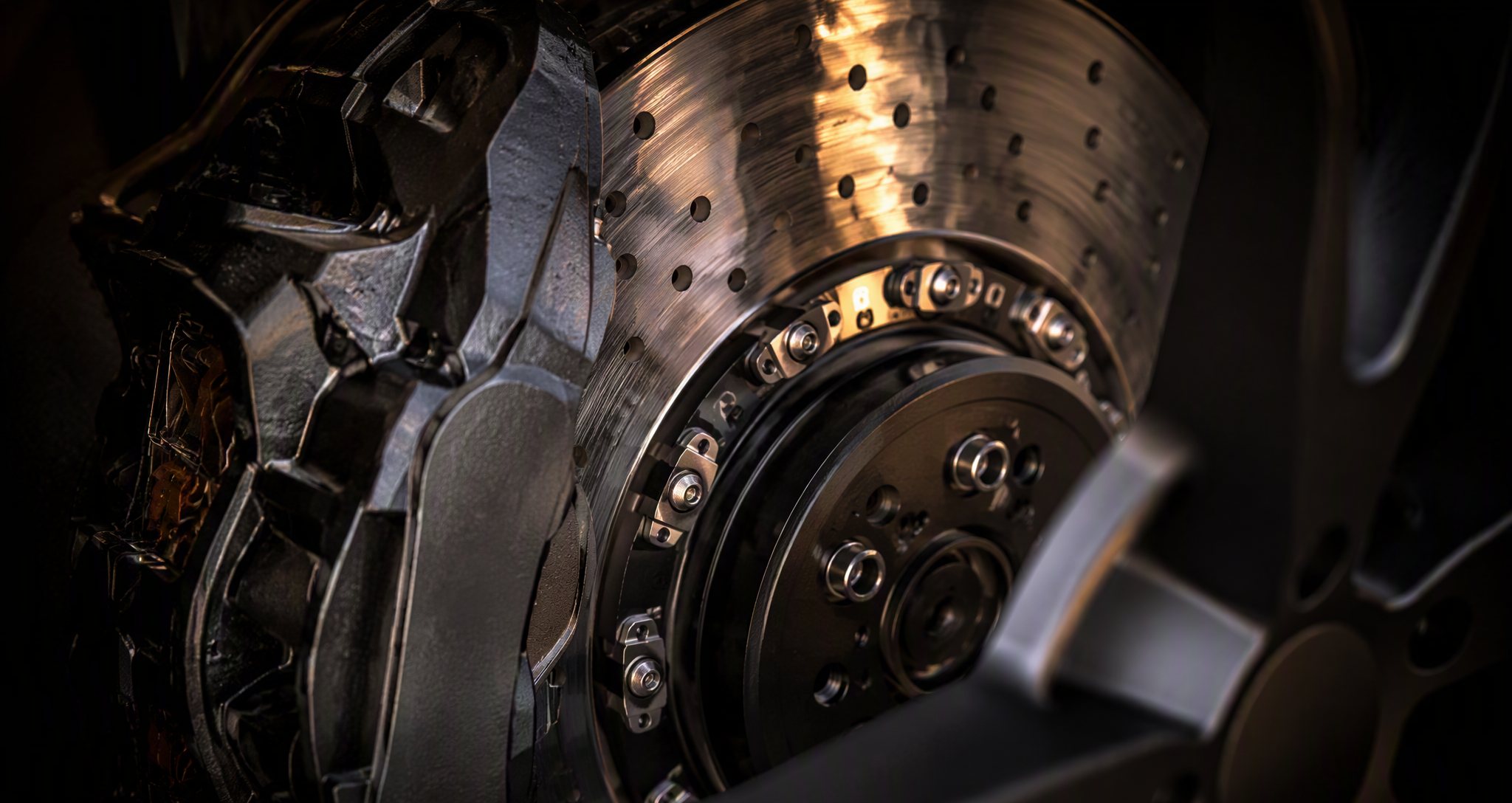 Close-up of a brake disc and caliper in warm workshop light